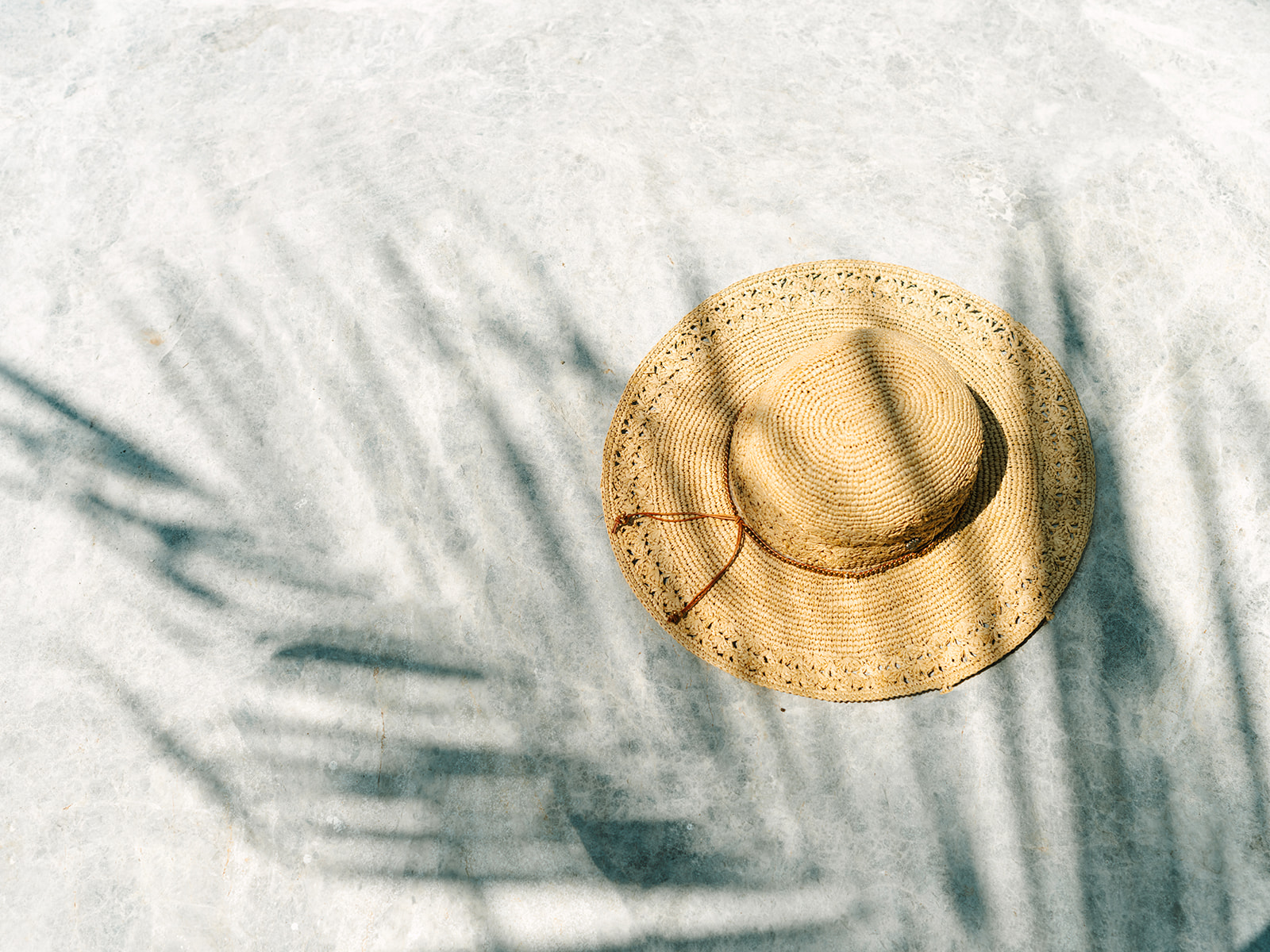 straw sunhat with tree branch shadows